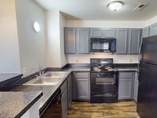 A kitchen with a black refrigerator, stove, and oven.