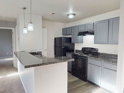 A kitchen with black appliances and a granite countertop.