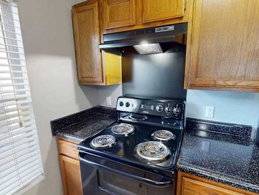 A black stove top oven with four burners and a silver pot on the left side.