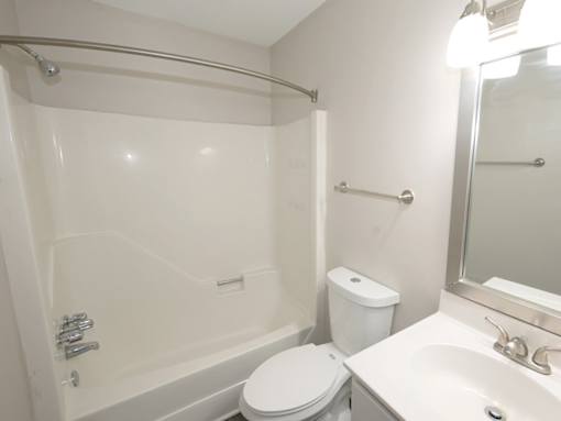 A white bathroom with a toilet, sink, and shower.