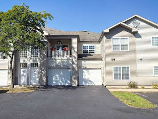 A two-story house with a garage and a tree in front.