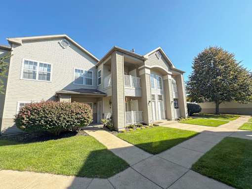 A two-story house with a well-maintained lawn and a clear blue sky above.
