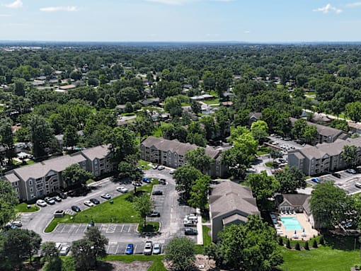 A bird's eye view of a residential area with houses, cars, and a pool.