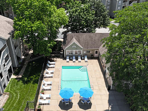 A pool surrounded by chairs and trees.