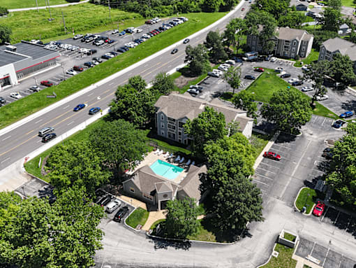 A bird's eye view of a parking lot with cars and a building with a pool.