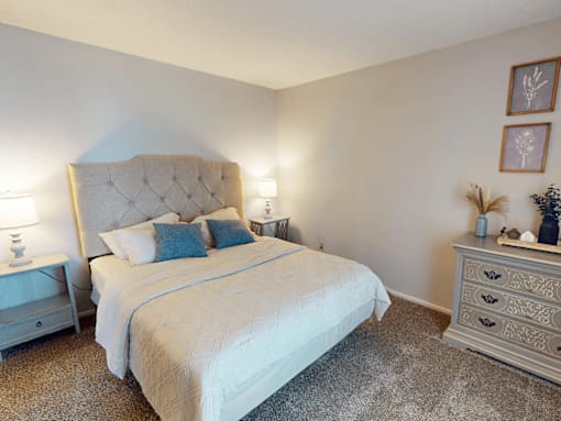 A bedroom with a large bed and a nightstand with a lamp.