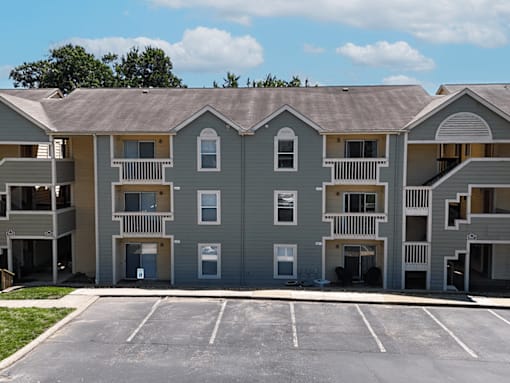 A large apartment complex with a parking lot in front.