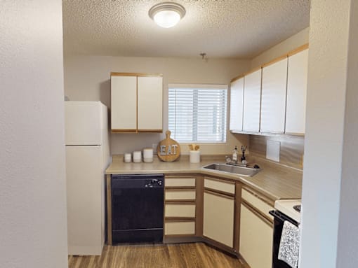 A kitchen with a white refrigerator, wooden cabinets, and a black oven.