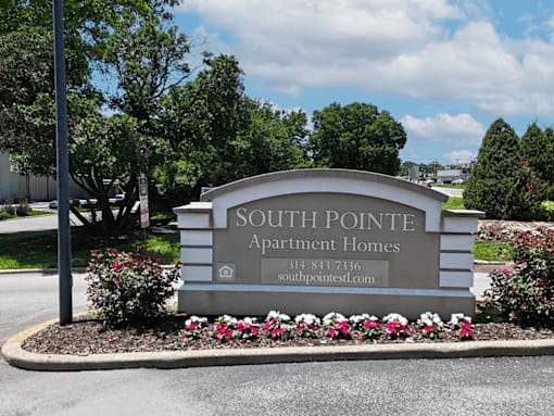 A sign for Southpointe Apartment Homes is surrounded by flowers and greenery.