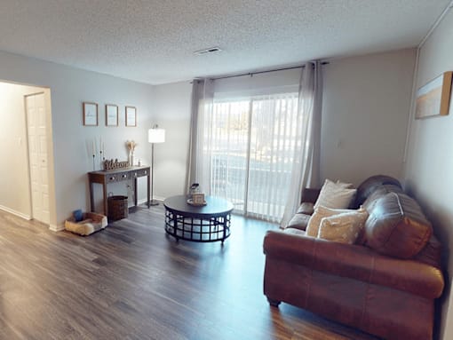 A living room with a brown leather couch and a glass coffee table.