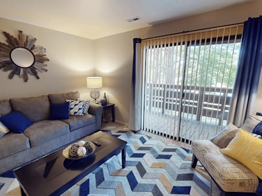 A living room with a grey couch, a coffee table, and a mirror on the wall.