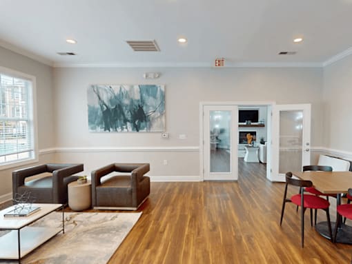 A living room with a large painting on the wall and a dining area in the background.