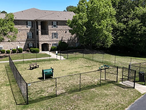 A large grassy area with a fence and a building in the background.