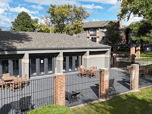A patio with a table and chairs is surrounded by a black fence.