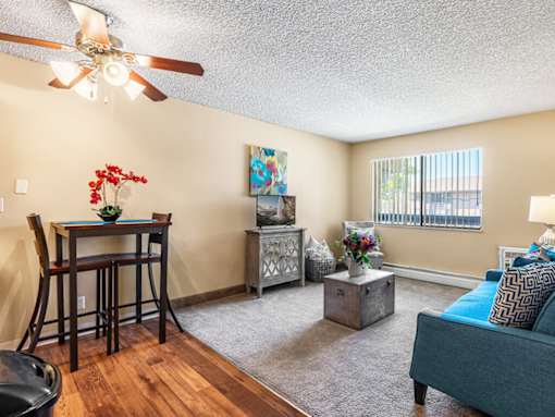 A living room with a blue couch and a wooden dining table.