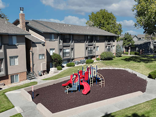 A playground with a red slide in the middle of a courtyard.