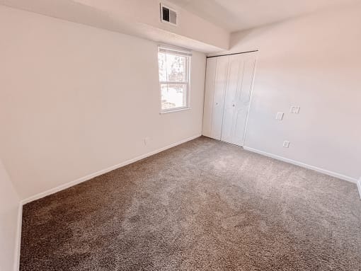an empty bedroom with carpeting and a door to a closet