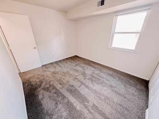 an empty room with carpet and a window