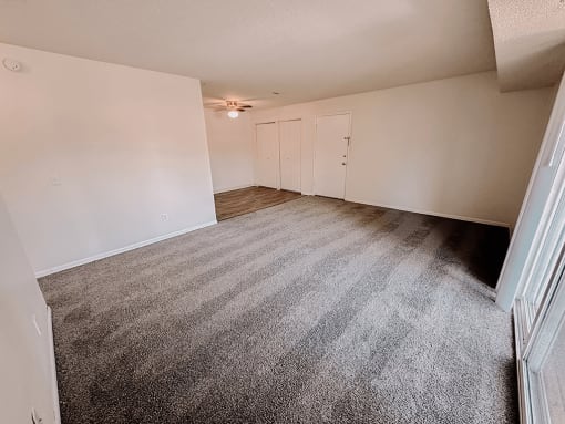 an empty living room with carpeting and white walls