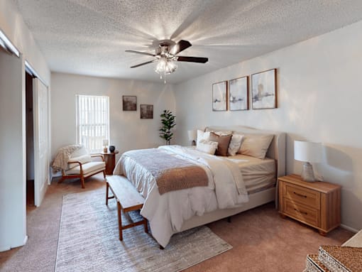 A bedroom with a bed, chair, and ceiling fan.