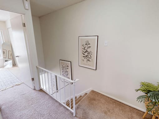 A baby's crib sits in a corner of a room with a framed picture on the wall above it.