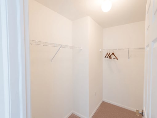 a closet with a white wall and a hanging rack on the wall