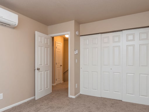 A room with a white door and a carpeted floor.