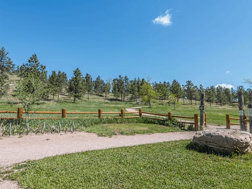 A pathway with a fence and a large rock in the foreground.