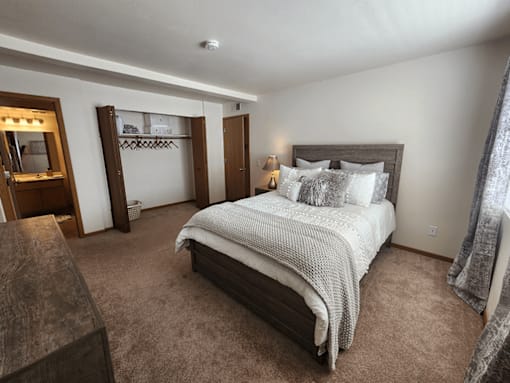 A bedroom with a large bed and a wooden headboard.