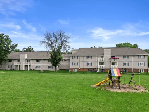a field of green grass and playground outside sun valley apartments