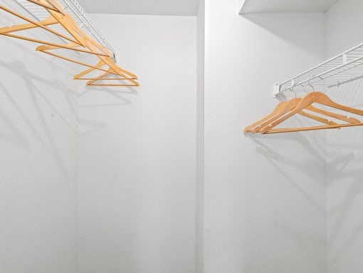 an empty closet with wooden clothes rack on the wall