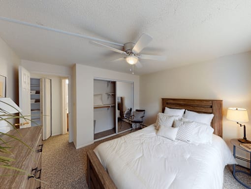 A bedroom with a large bed and a ceiling fan.