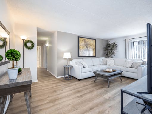 A living room with a white couch, a coffee table, and a flat screen TV.