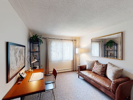 A living room with a brown couch, a wooden table, and a chair.
