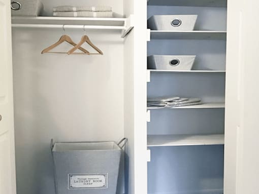 A laundry room sign is on a grey bag in a white closet.