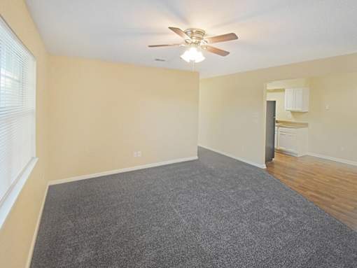 A room with a ceiling fan and carpeted floor.