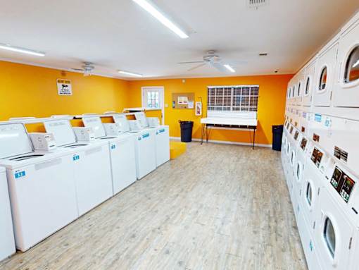 A laundromat with rows of washing machines and a fan on the ceiling.