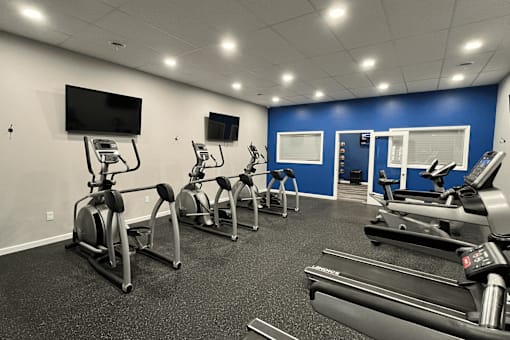 A gym with treadmills, exercise bikes, and a television.