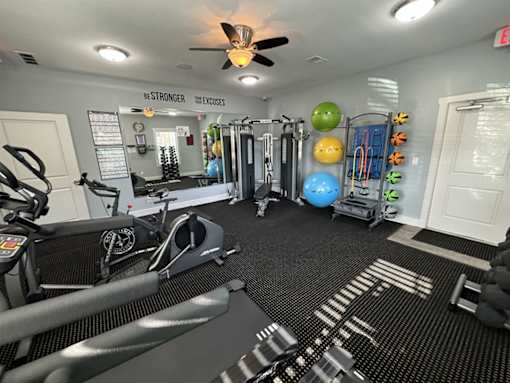 A gym with a variety of equipment including treadmills, weights, and exercise balls.