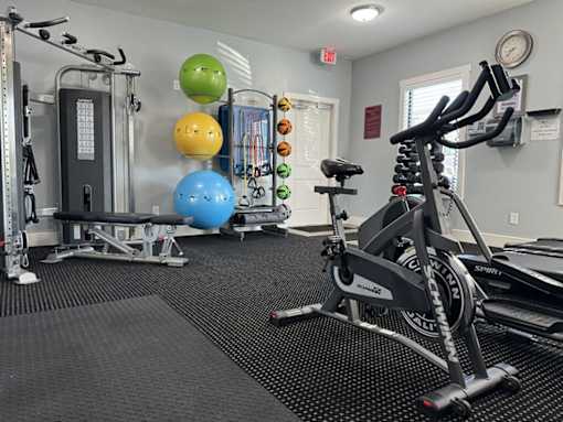 A gym with a rowing machine, a bench, and a wall-mounted clock.