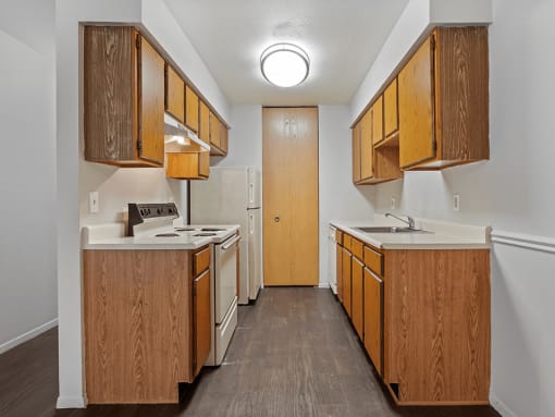 apartment kitchen with wood cabinets and white appliances