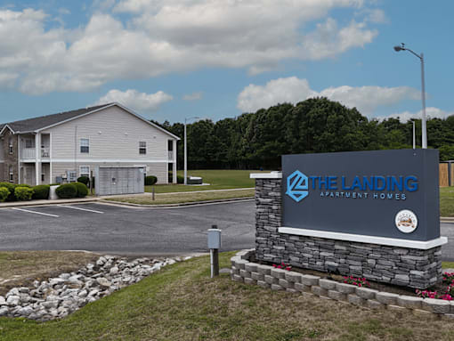 A sign for The Landing Apartment Homes stands in front of a building.