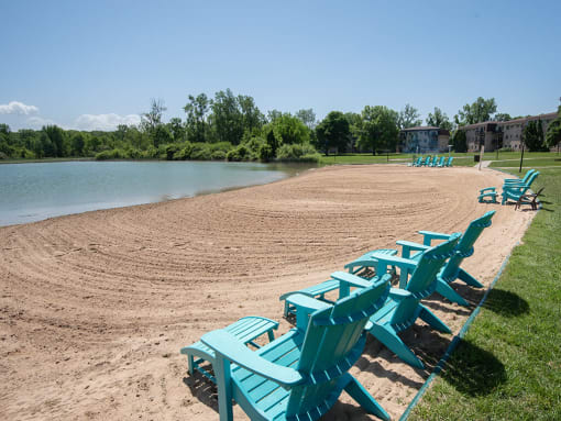a row of blue beach chairs sitting on the sand near the water