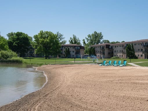 a beach with chairs near a body of water and buildings