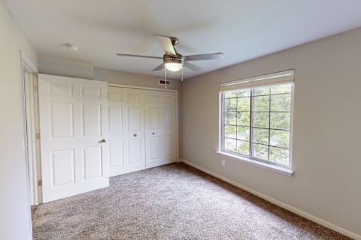 A room with a ceiling fan and a window.