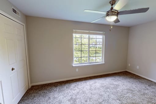 A room with a ceiling fan and a window.