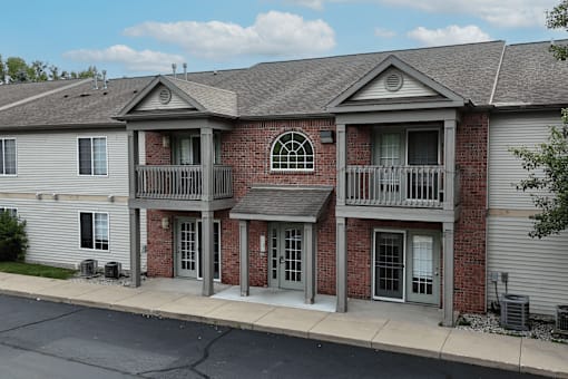 A two-story brick building with a grey roof and a balcony on the second floor.
