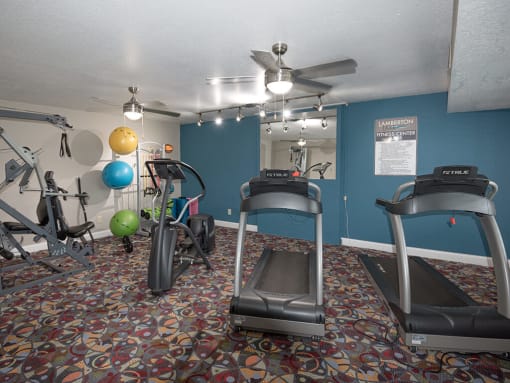 a gym with exercise equipment and a ceiling fan