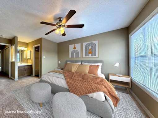 A bedroom with a bed, a ceiling fan, and a nightstand.