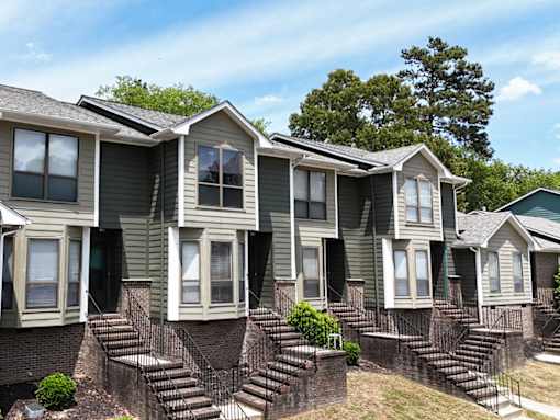 A row of houses with green siding and white trim.